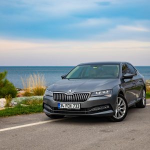 A sleek grey Skoda Superb sedan parked by a scenic seaside in Sinop, Türkiye.